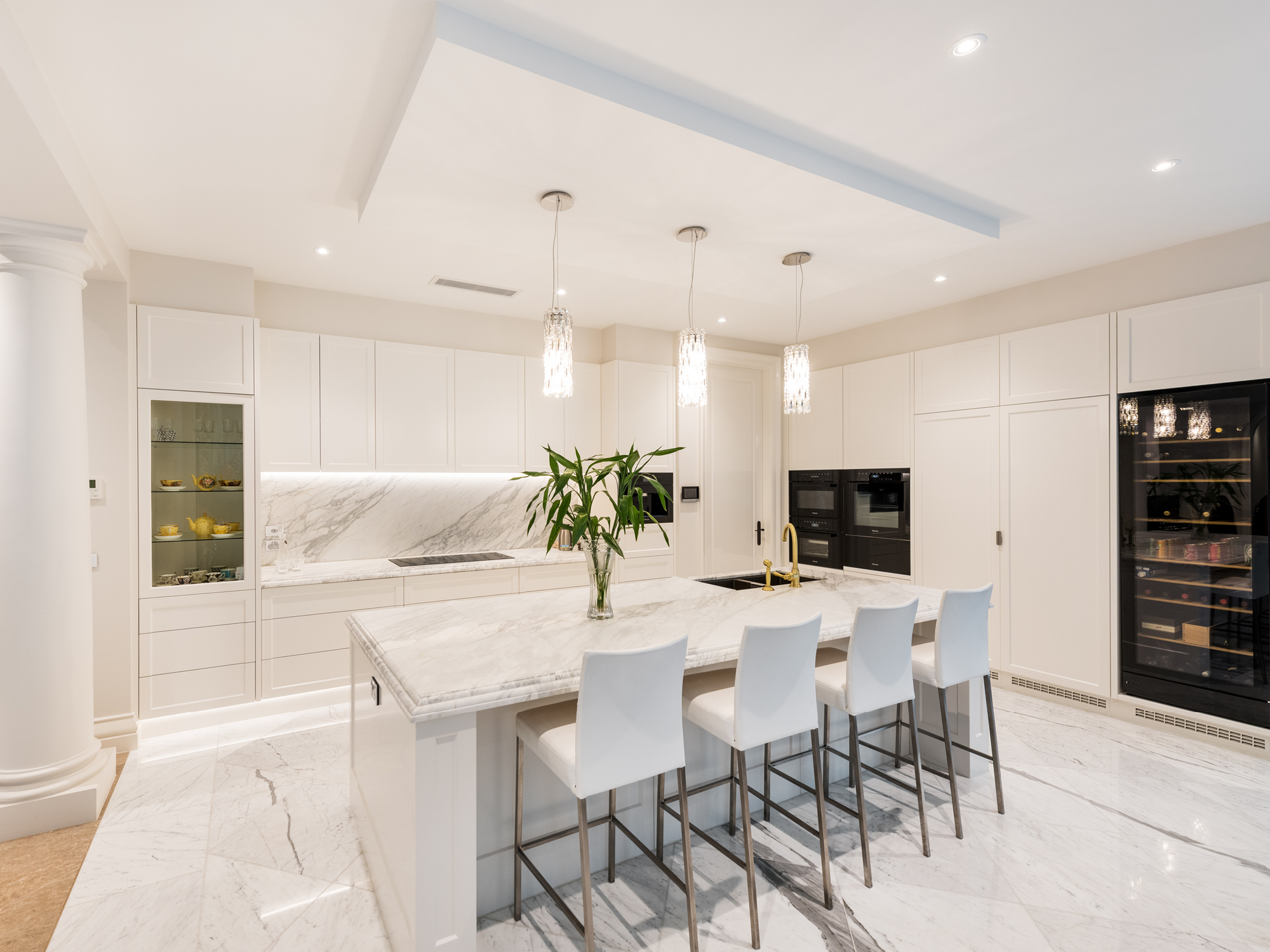A Grand residence kitchen, with white stone floors and benches.