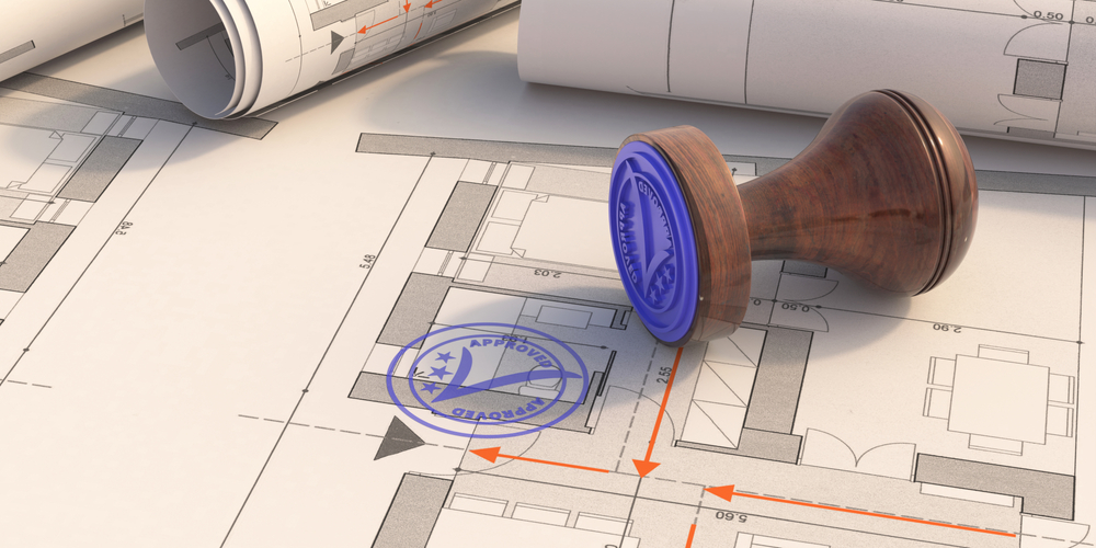 Architectural blueprints with an approved stamp on top.